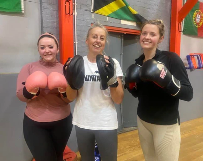Three Revenge members together after training, smiling with their gloves on